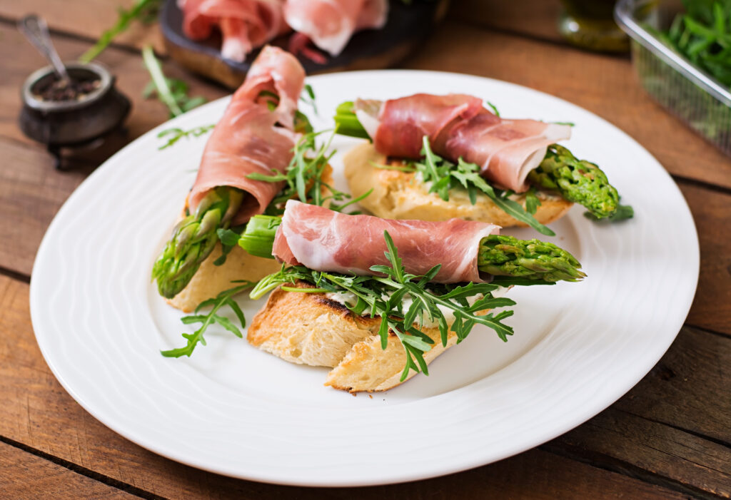 Jamón serrano enrollando espárragos